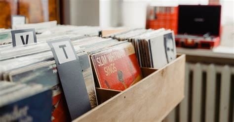 Stack of vintage records in a wooden box, worn sleeves peeking out.